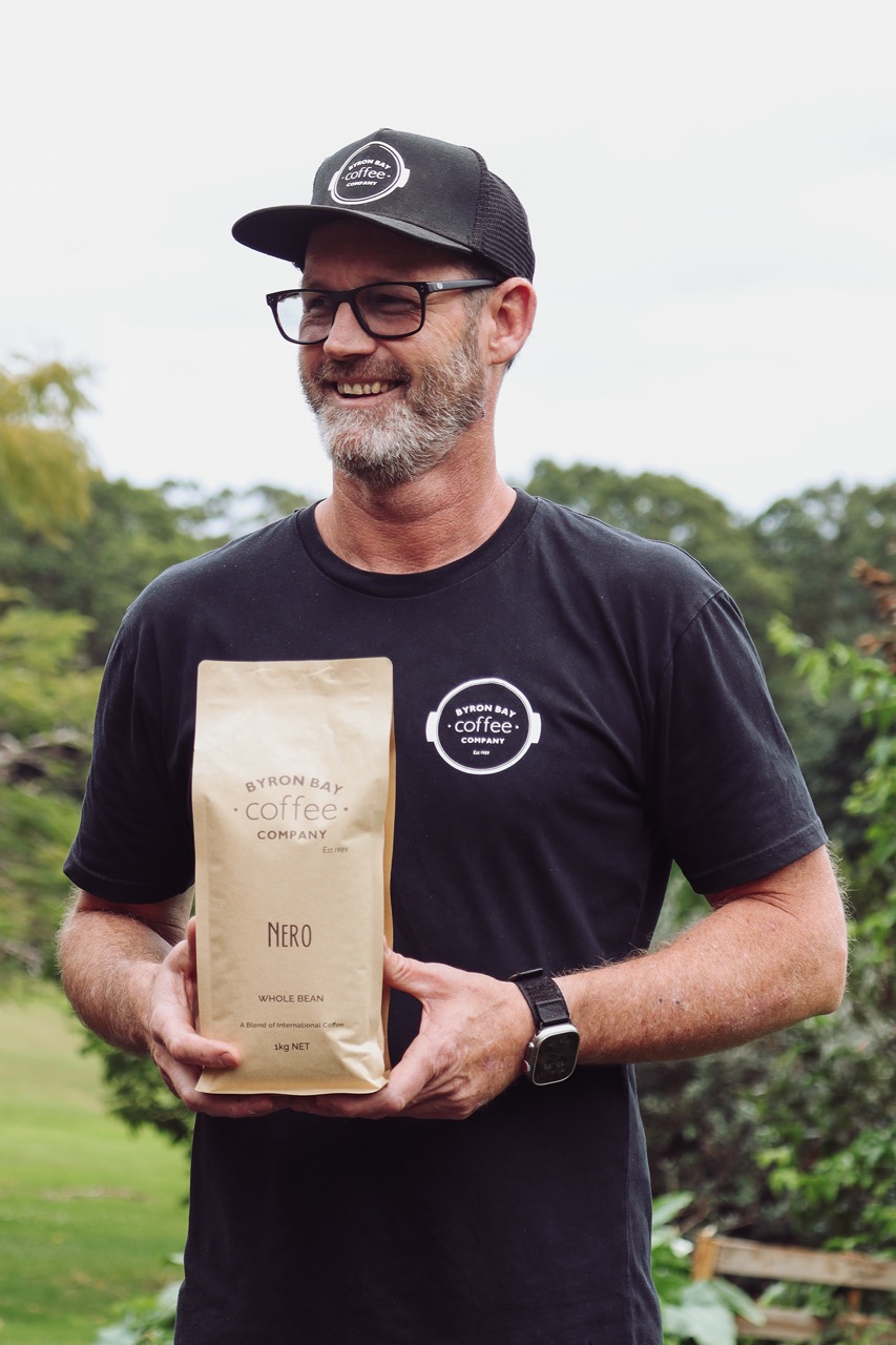 Man Holding Organic Coffee Kilo Pack Wearing a Byron Bay Coffee Company Trucker Hat